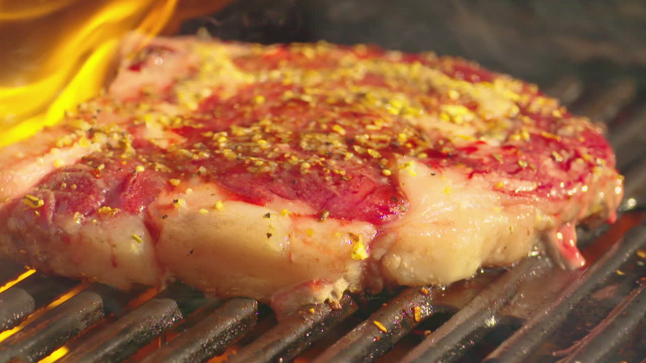 delicioso bistec cocinado en una parrilla de barbacoa en llamas