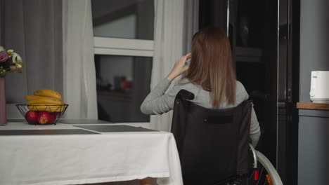 mujer con discapacidad se sienta en la cocina bebiendo agua