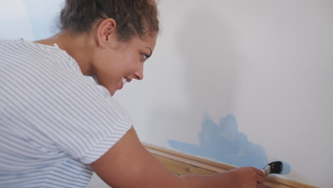 young woman decorating room in new home painting wall with brush