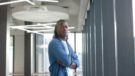 confident man standing with arms crossed in modern office building