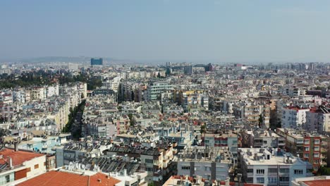 Drone-Aéreo-Volando-Bajo-Sobre-Los-Tejados-De-Edificios-De-Apartamentos-Residenciales-En-Un-Barrio-Densamente-Poblado-De-Antalya-Turquía-En-Un-Día-Soleado-De-Verano