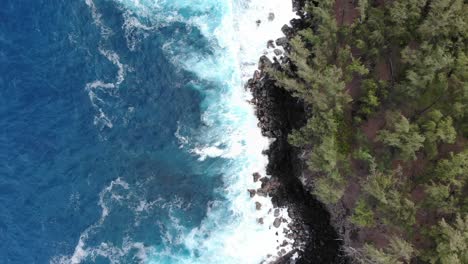 Travelling-with-a-drone-looking-down-on-coastline-of-volcanic-eruption-on-Hawaii-with-waves-crashing-onto-black-stone-beaches