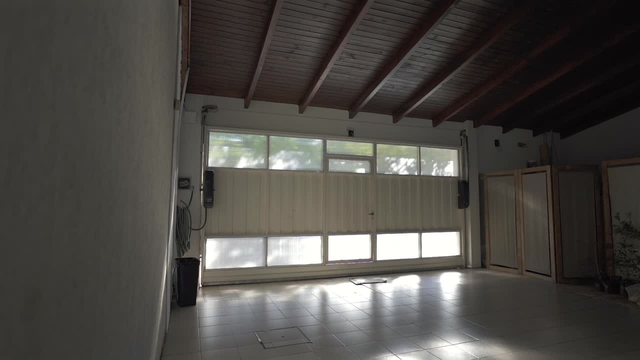 Spacious empty house garage for cars with large windows and wooden ceiling.