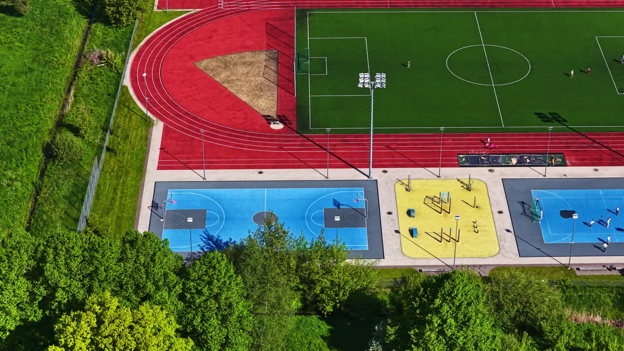 Colorful sports complex with soccer field, tracks, courts and gym area, aerial view