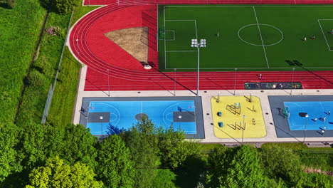 colorful sports complex with soccer field, tracks, courts and gym area, aerial view