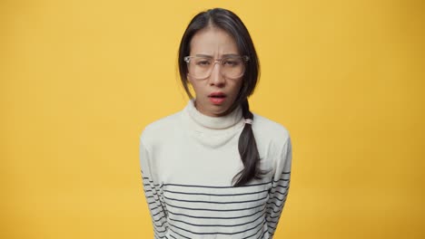 asia lady displeased upset angry screaming out loud and pulling her hair out isolated on the yellow background.