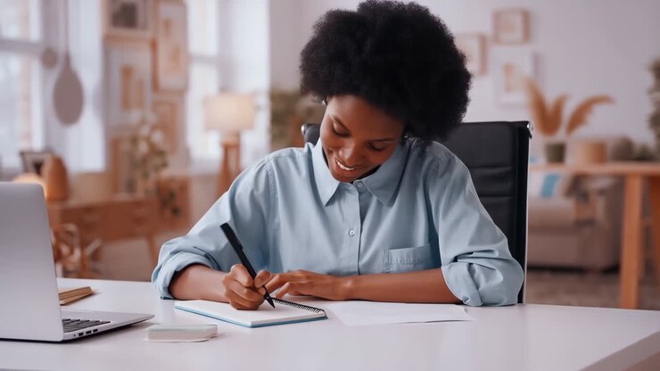 Donna che scrive in un quaderno alla sua scrivania