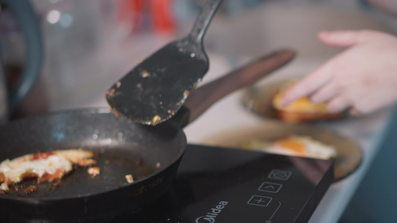 Frying egg in pan, stovetop spatula moves. Redhaired woman transfers crispy edged egg to plate, focused profile and steady hands, soft morning light, sizzling sound and warm kitchen atmosphere, simple