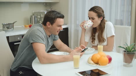 cheerful couple eating breakfast at kitchen together.