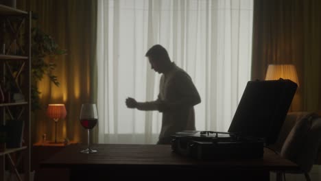 man dancing at home with wine and record player