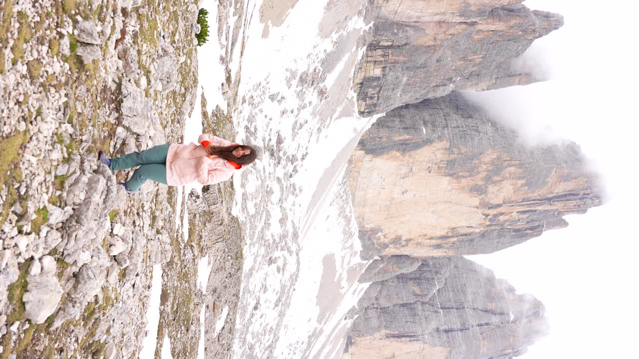 tomada vertical de una mujer linda disfrutando de una caminata en el nevado tre cime di lavaredo
