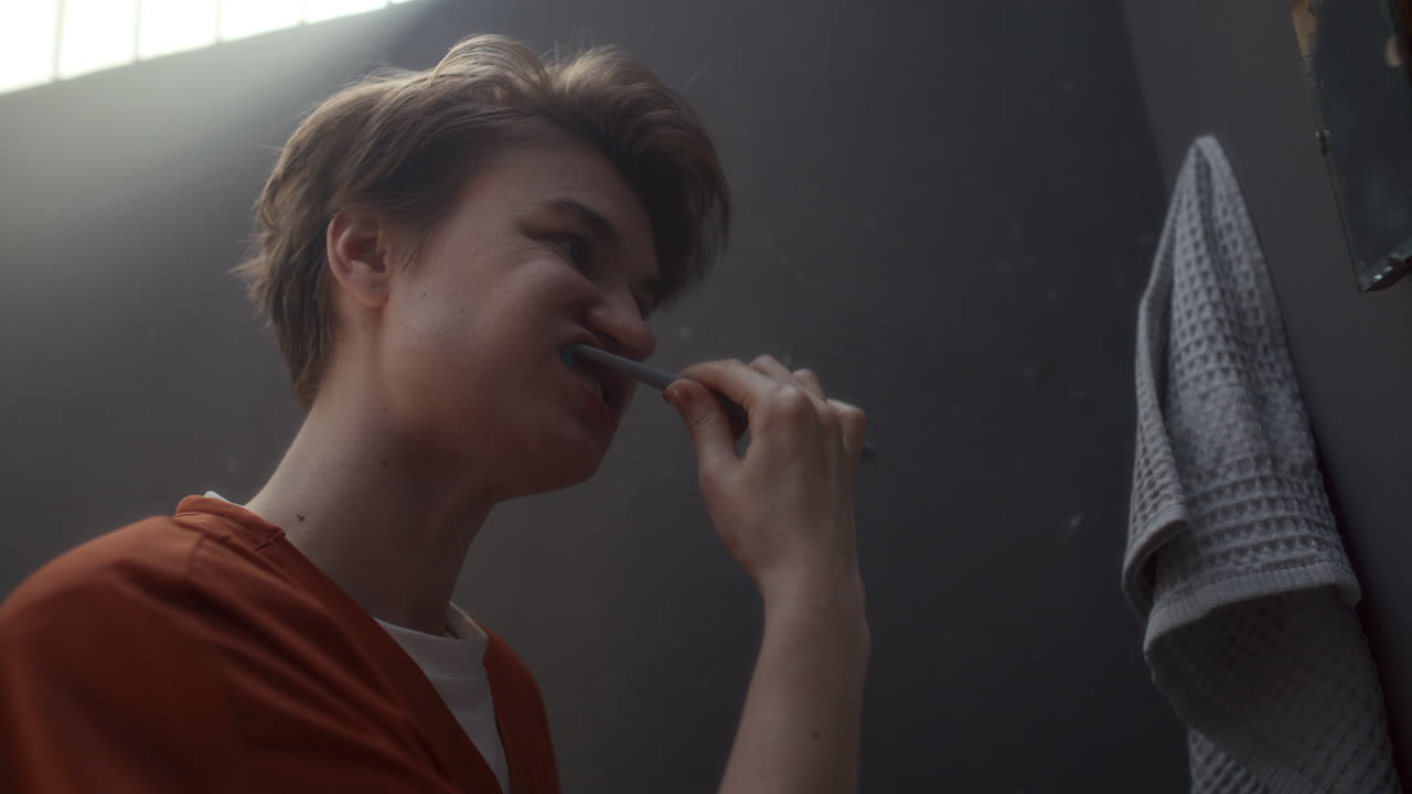 Female Prisoner Brushing Her Teeth and Looking in Mirror on Wall