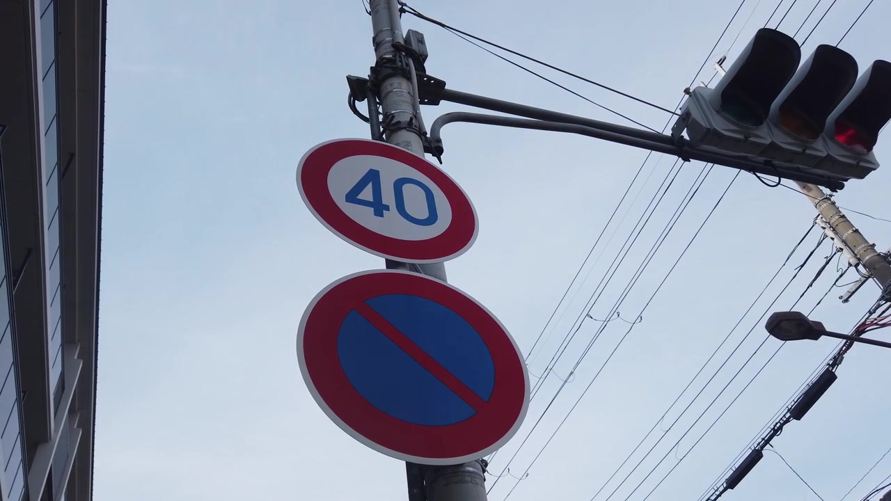 Froschperspektive von wechselnden Ampeln, Schildern und Kabeln in der städtischen Infrastruktur von Kyoto, Japan