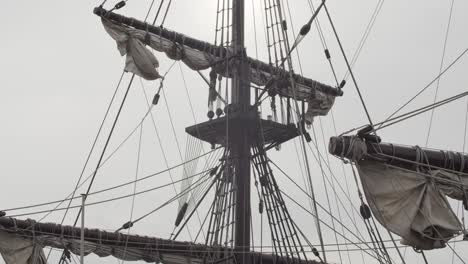 galleon andalucia replica ship detail tilt shot of the mainmast, roundhouse and sails against the sun while docked in valencia in slow motion 60fps