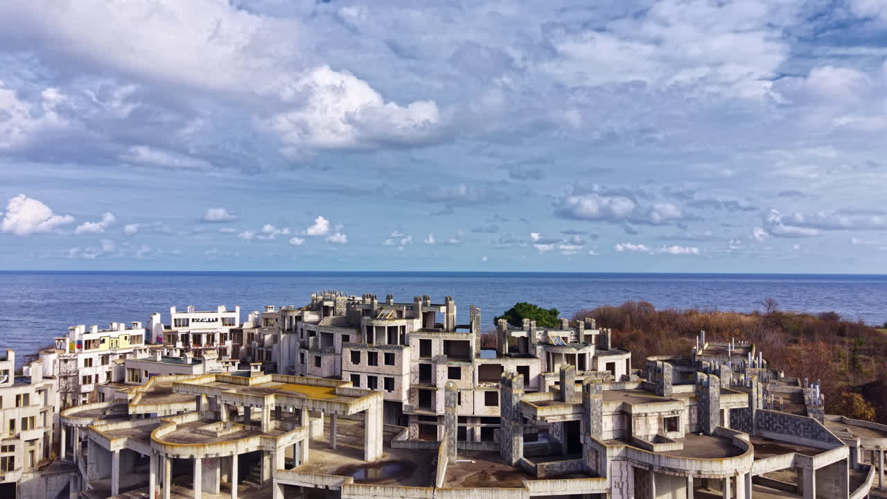 Un cantiere abbandonato in un paesaggio costiero con nuvole intense e l'oceano in lontananza cattura l'essenza del degrado e il tocco rigenerante della natura.