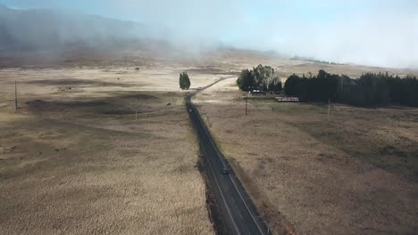 Vista-Aérea-Inclinándose-Hacia-Arriba-Para-Revelar-La-Conducción-De-Automóviles-A-Través-Del-Campo-De-La-Isla-De-Hawaii