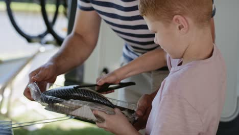 Close-up-video-of-little-boy-grilling-a-fish-with-father