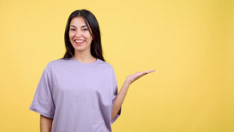 smiling woman presenting or showing something with an open hand gesture on a yellow background