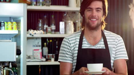 male waiter holding a cup of coffee