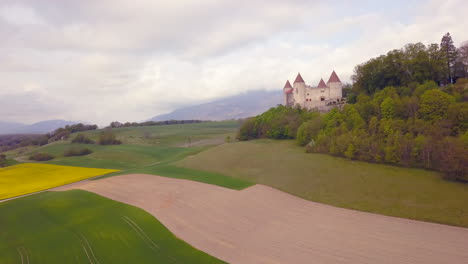 cultivated fields around champvent castle, switzerland. aerial rising