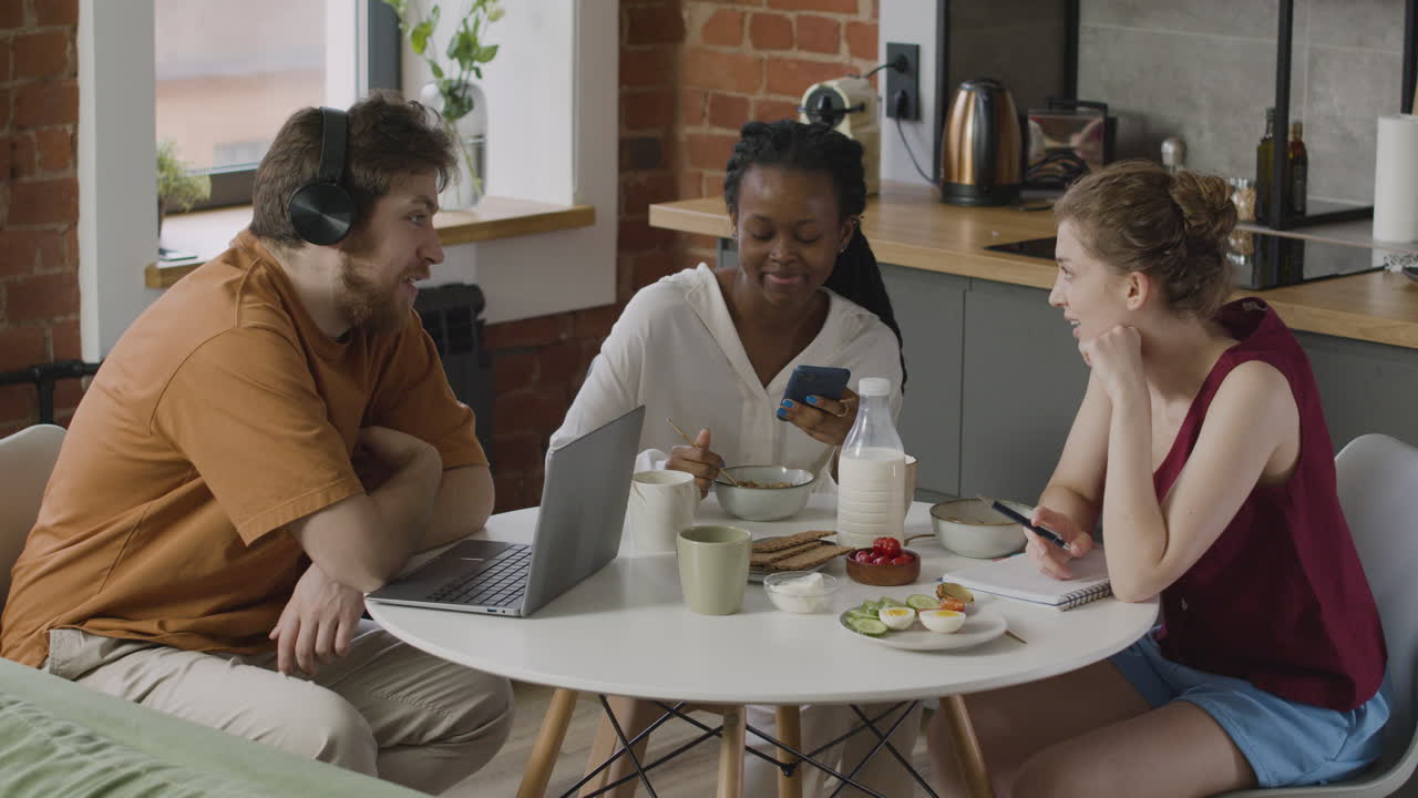 tres compañeros sentados en la cocina y hablando juntos durante el desayuno