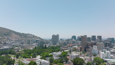 Slide-and-pan-footage-of-urban-borough-on-sunny-day.-Various-buildings-and-trees-in-park.-Cape-Town,-South-Africa