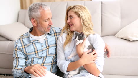 pareja feliz con su gatito en el suelo