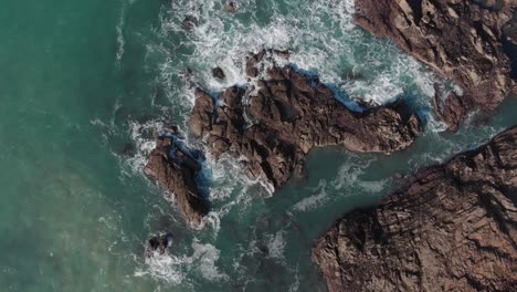 Aerial-Stationary-Shot-Of-Rocks-Being-Hit-By-Big-Waves,-Plemont-Bay,-Jersey,-Channel-Islands,-4k