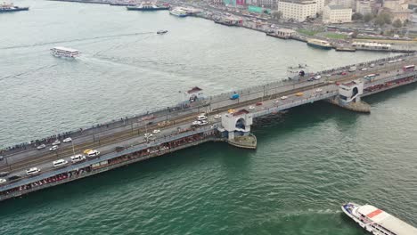 Luftdrohne-Umkreist-Die-Galata-Brücke-Bei-Sonnenaufgang,-Während-Autos-Und-Busse-Den-Bosporus-überqueren