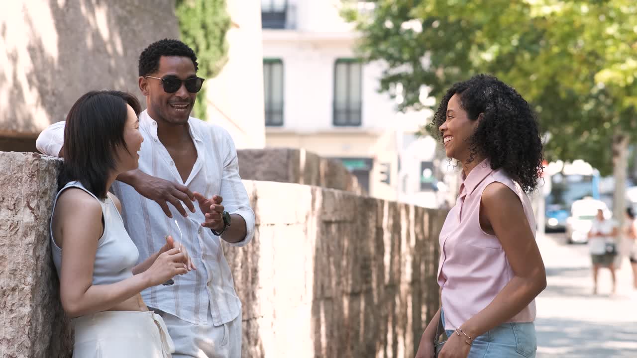 Multiethnic friends talking while standing on sidewalk in city during daytime