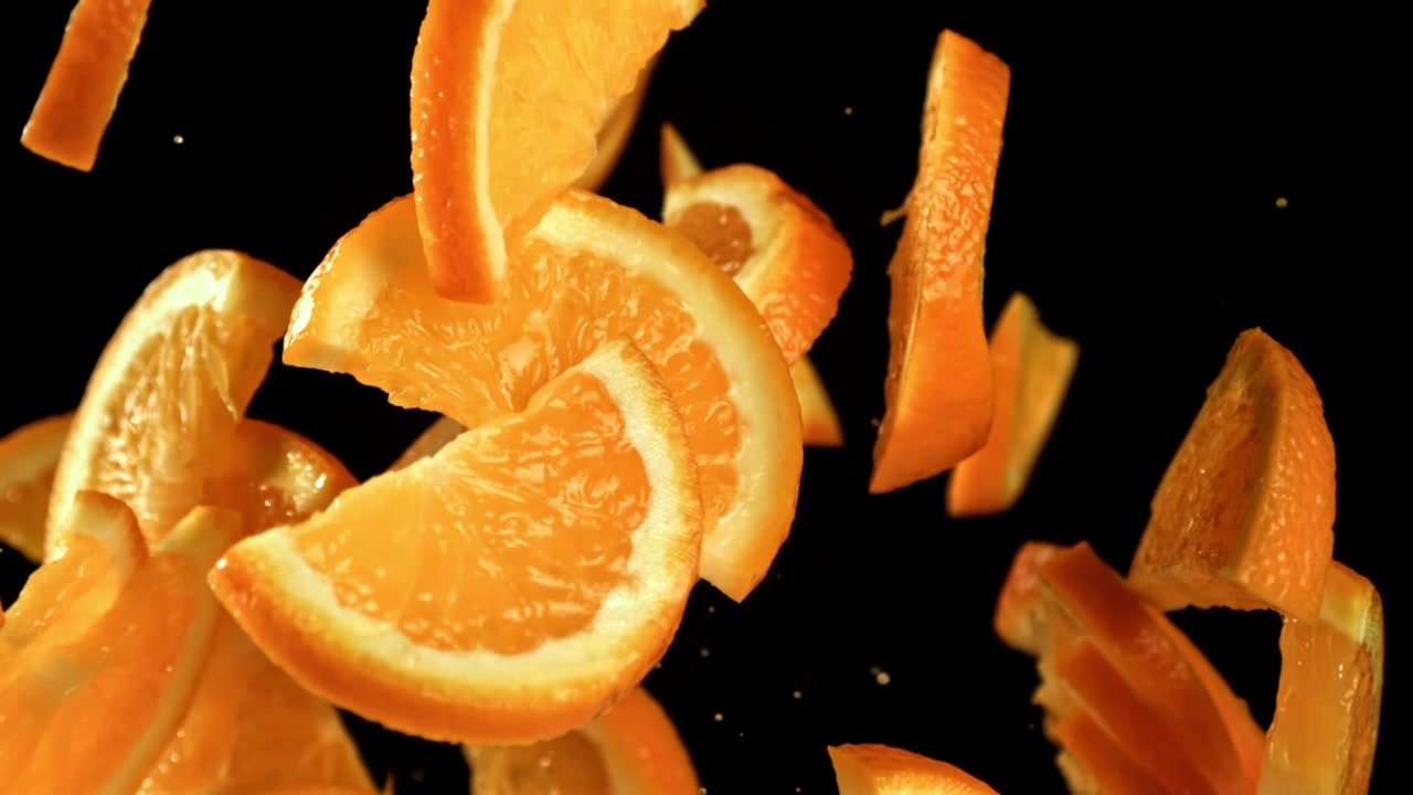 Fatias de laranja frescas caindo em câmera lenta em fundo preto