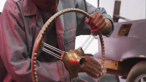 african american male car mechanic cleaning a steering wheel with a rag