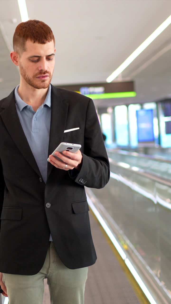 Man on Moving Walkway in Airport Using Smartphone