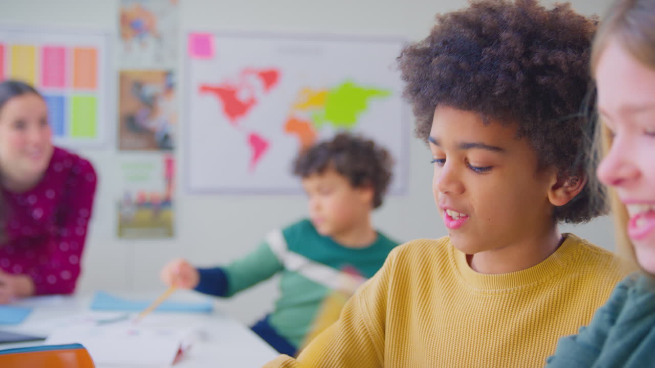 grupo de estudiantes multiculturales levantando las manos para responder a una pregunta en la lección de geografía en el aula