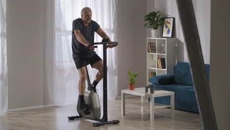 actividad deportiva en el hogar hombre de mediana edad está usando bicicleta estacionaria en la sala de estar estilo de vida saludable para las personas en auto-aislación