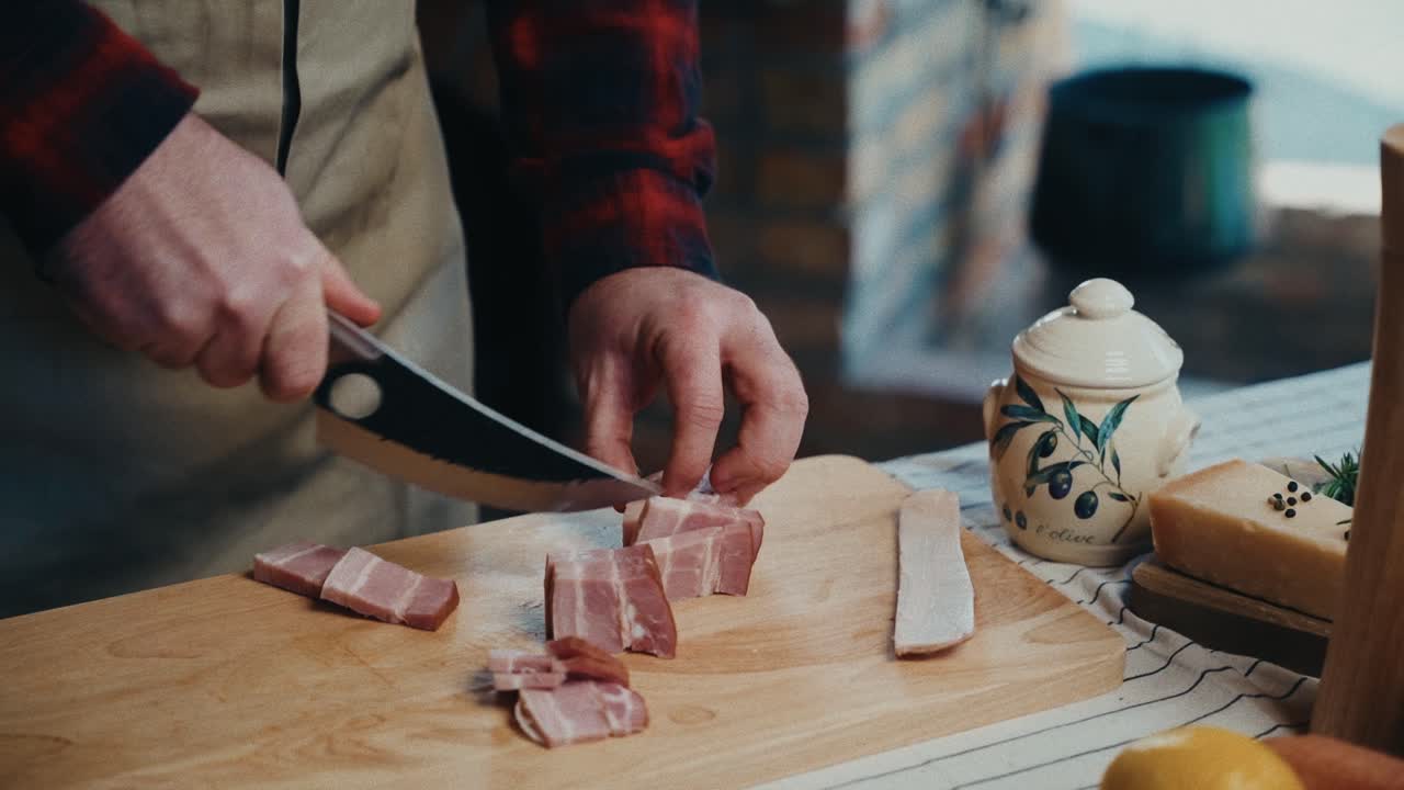 한 사람 이 조리용 재료 를 준비 하고 있는 나무 의 절단판 에 베이컨 을 잘라 낸다