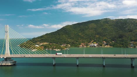 Concrete-cable-stayed-bridge-traffic-above-turquoise-color-ocean-drone-aerial-side-panning-view-of