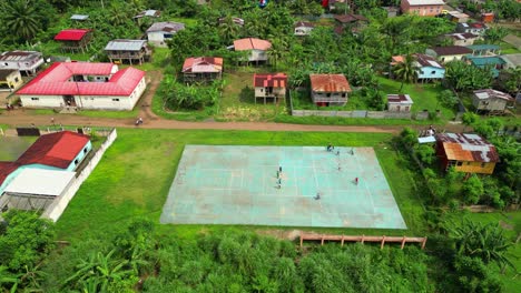 aerial view of children playing ball and riding bikes with ribeira afonso village in the background. são tomé,africa