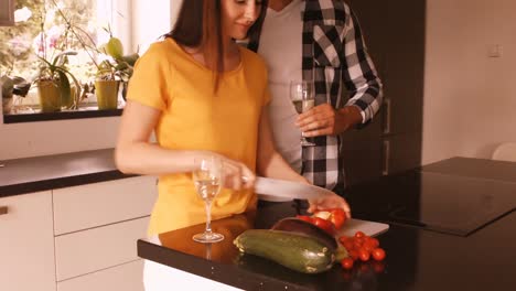 woman chopping vegetable while man having champagne