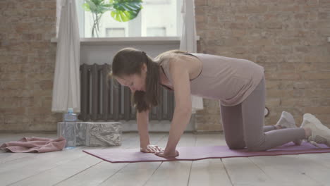 anciana haciendo flexiones en la estera de yoga en casa