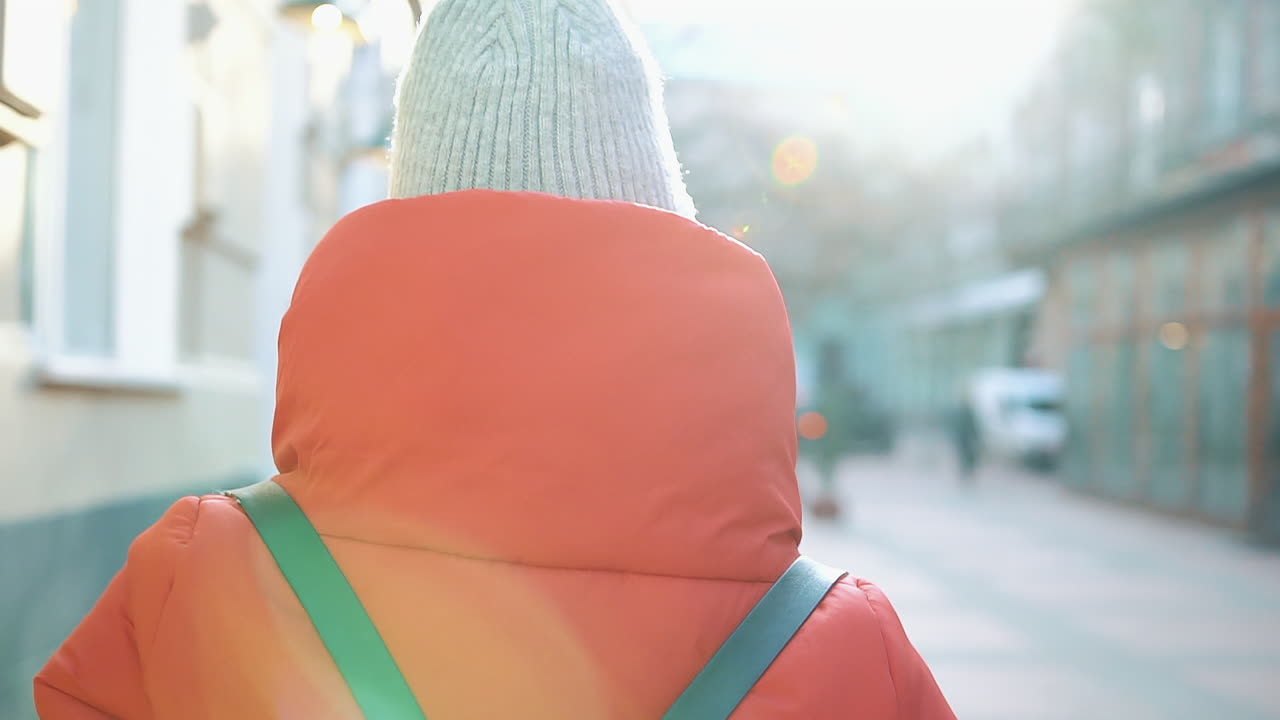 Woman in red coat and beanie on urban street