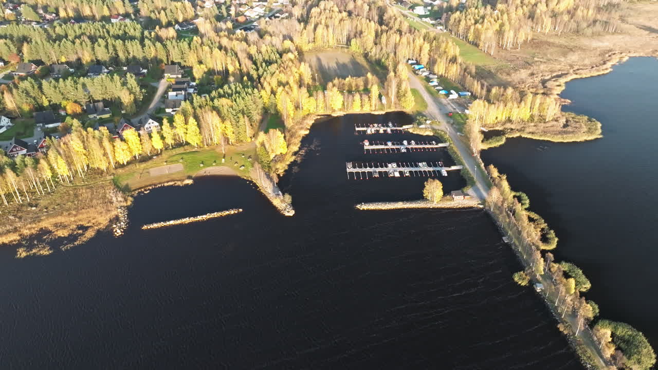스웨덴의 가을의 소나무로 둘러싸인 마리나 위의 해가 지는 모습