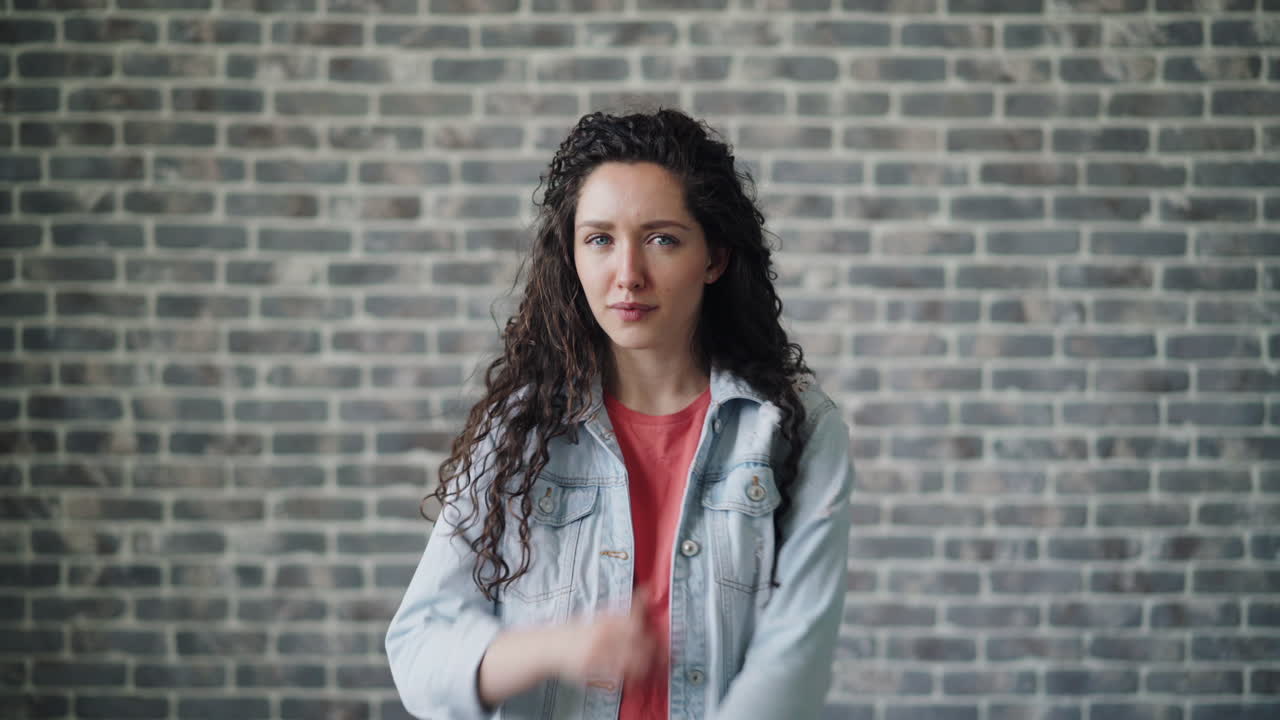 Woman with curly hair in front of brick wall