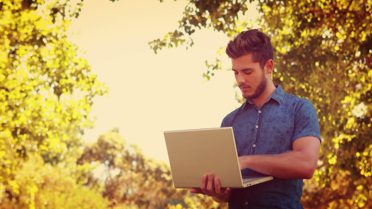 hombre guapo usando una computadora portátil en el parque
