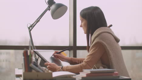 a young designer girl draws on a modern graphic screen using a workstation in an office with large windows. create logo design and graphics