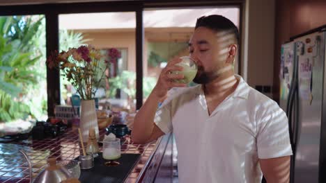 man enjoying matcha latte in the kitchen