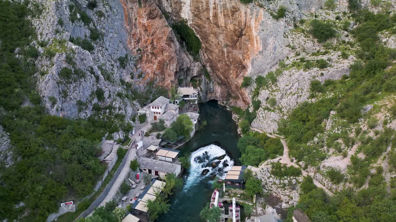 Drone shot approahing Blagaj Monastary in Mostar, Bosnia. A river running under a mountain with the building built into the rocks