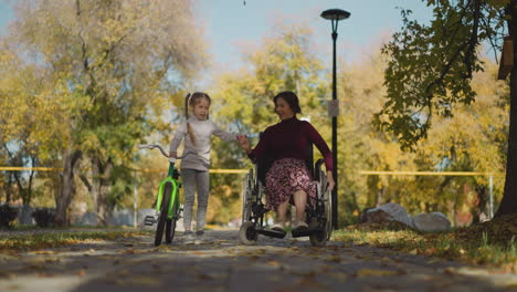 Mother-in-wheelchair-and-daughter-with-bicycle-rest-together