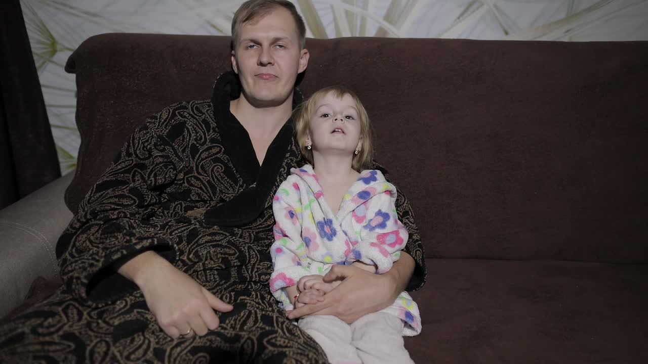 Figlia piccola con suo padre che guardano un film interessante con grande emozione.