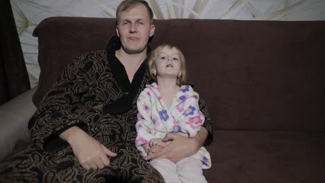 pequeña hija con su padre viendo una película interesante con grandes emociones